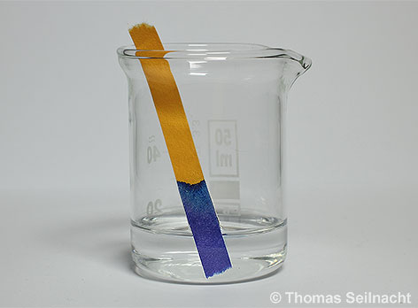 Ein Universal-Indikatorpapier färbt sich in Natronlauge blau